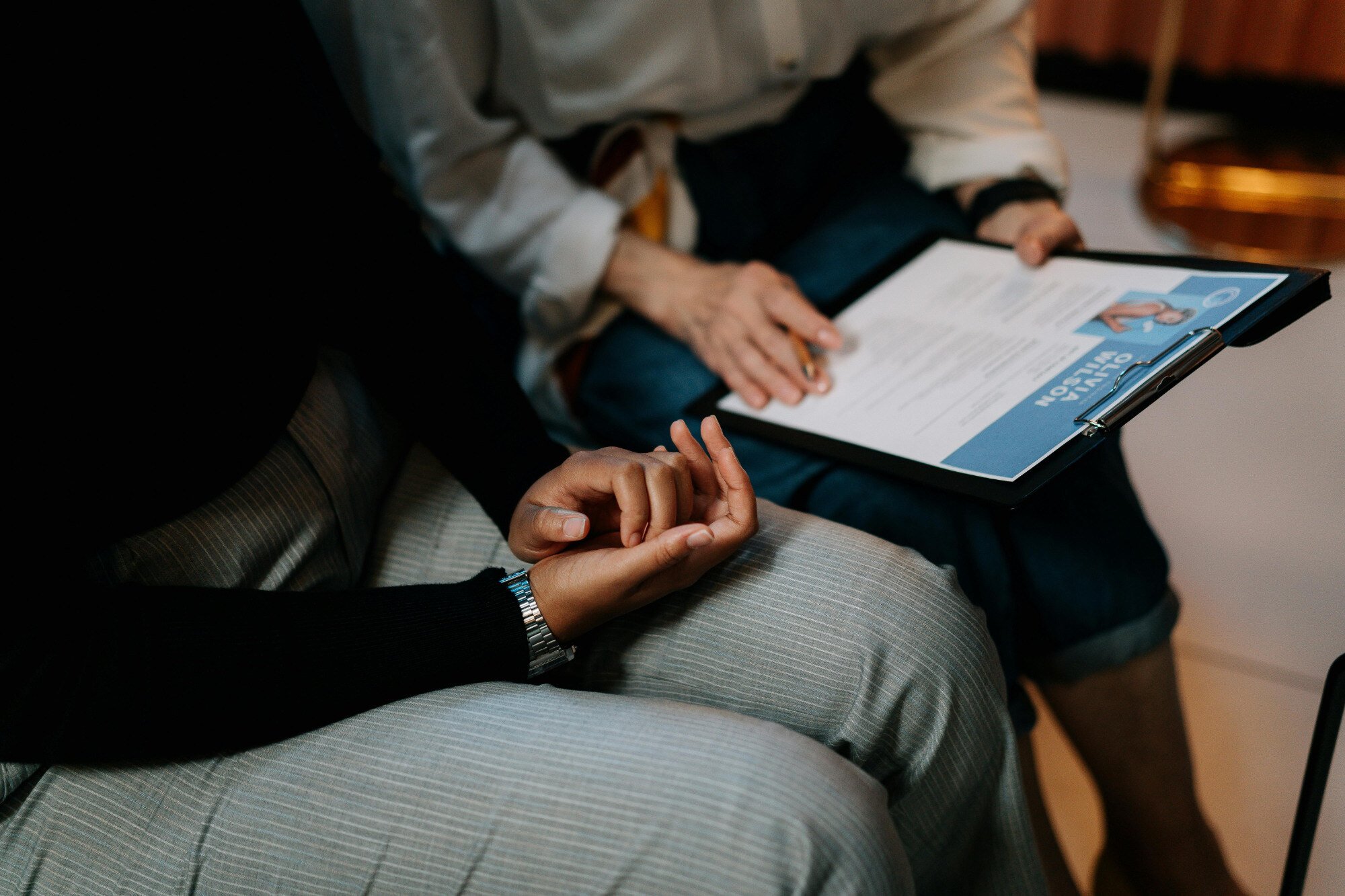 Two office workers sat side by side looking at resume.