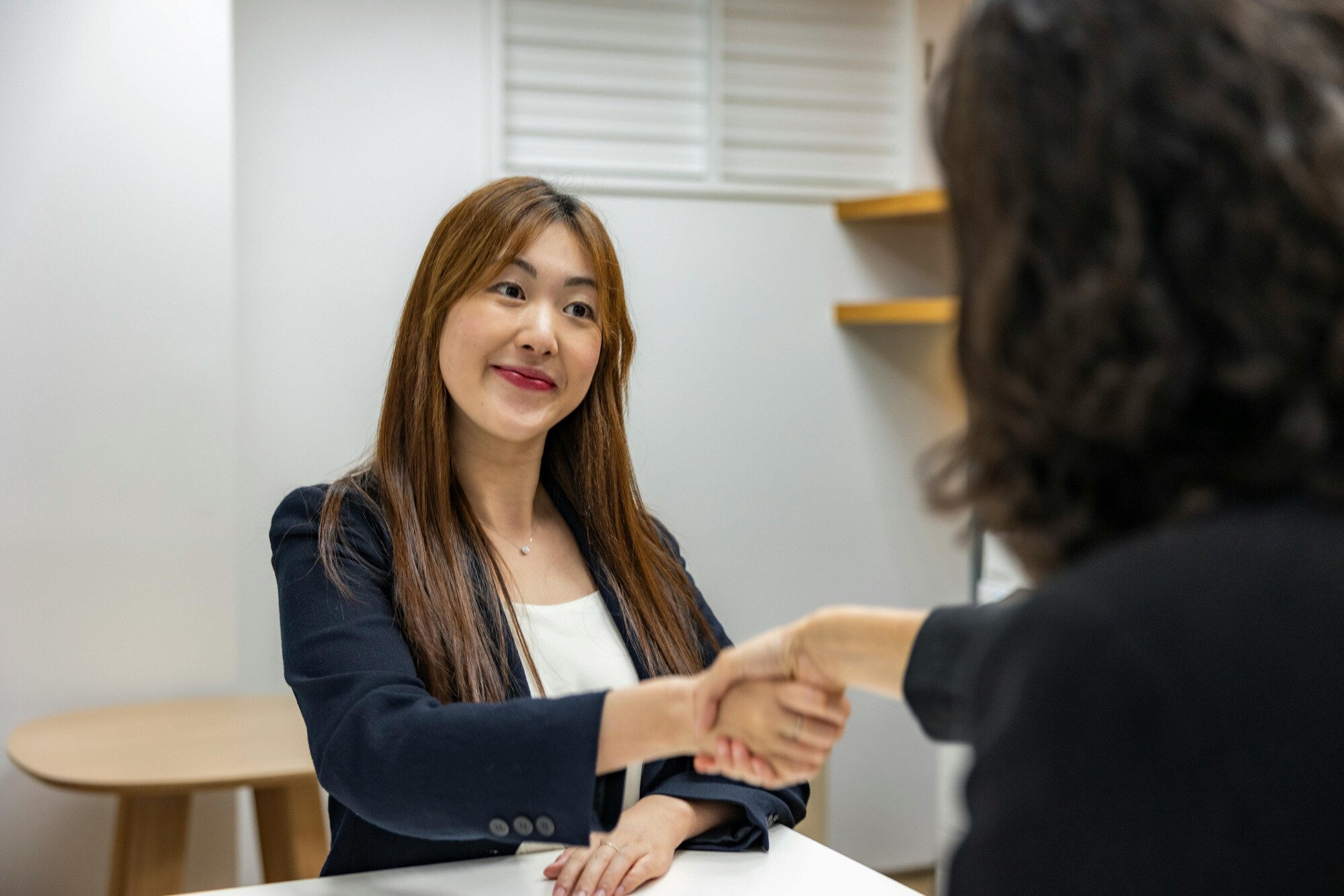 An interviewee smiling while shaking hands with interviewer.