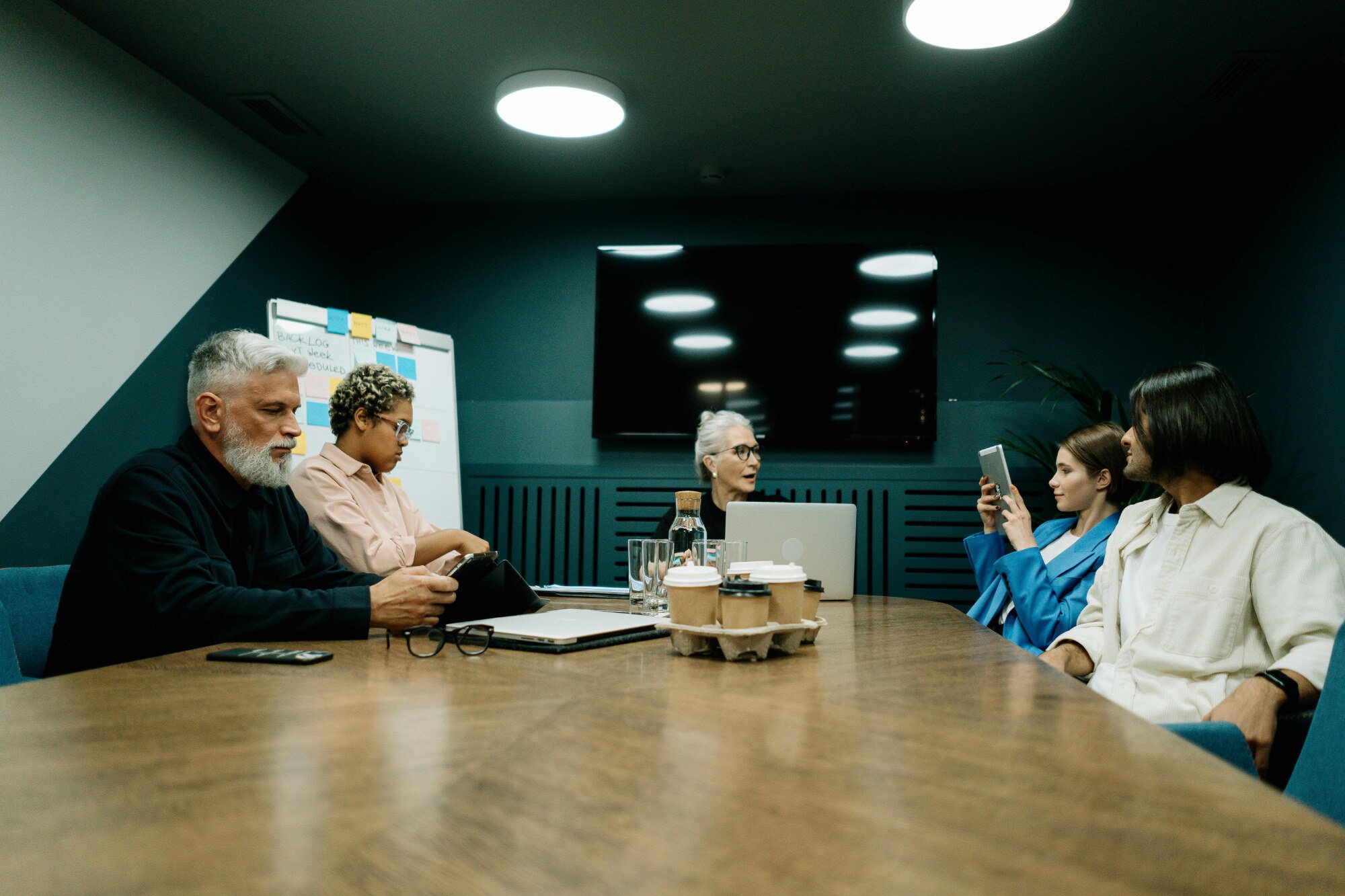 People sitting at the end of a long desk having an office meeting.