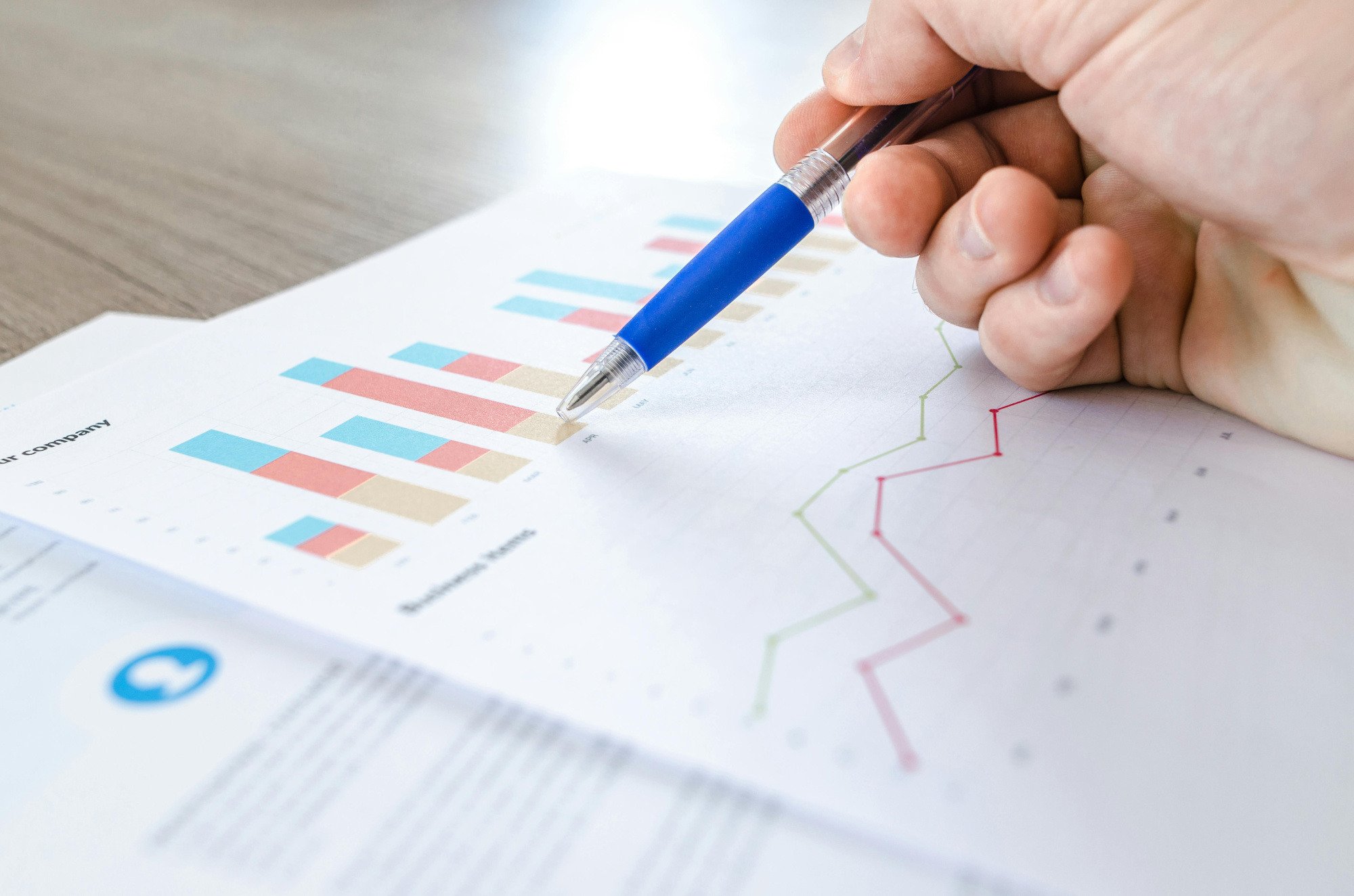 Somebody pointing to statistics graph with pen.