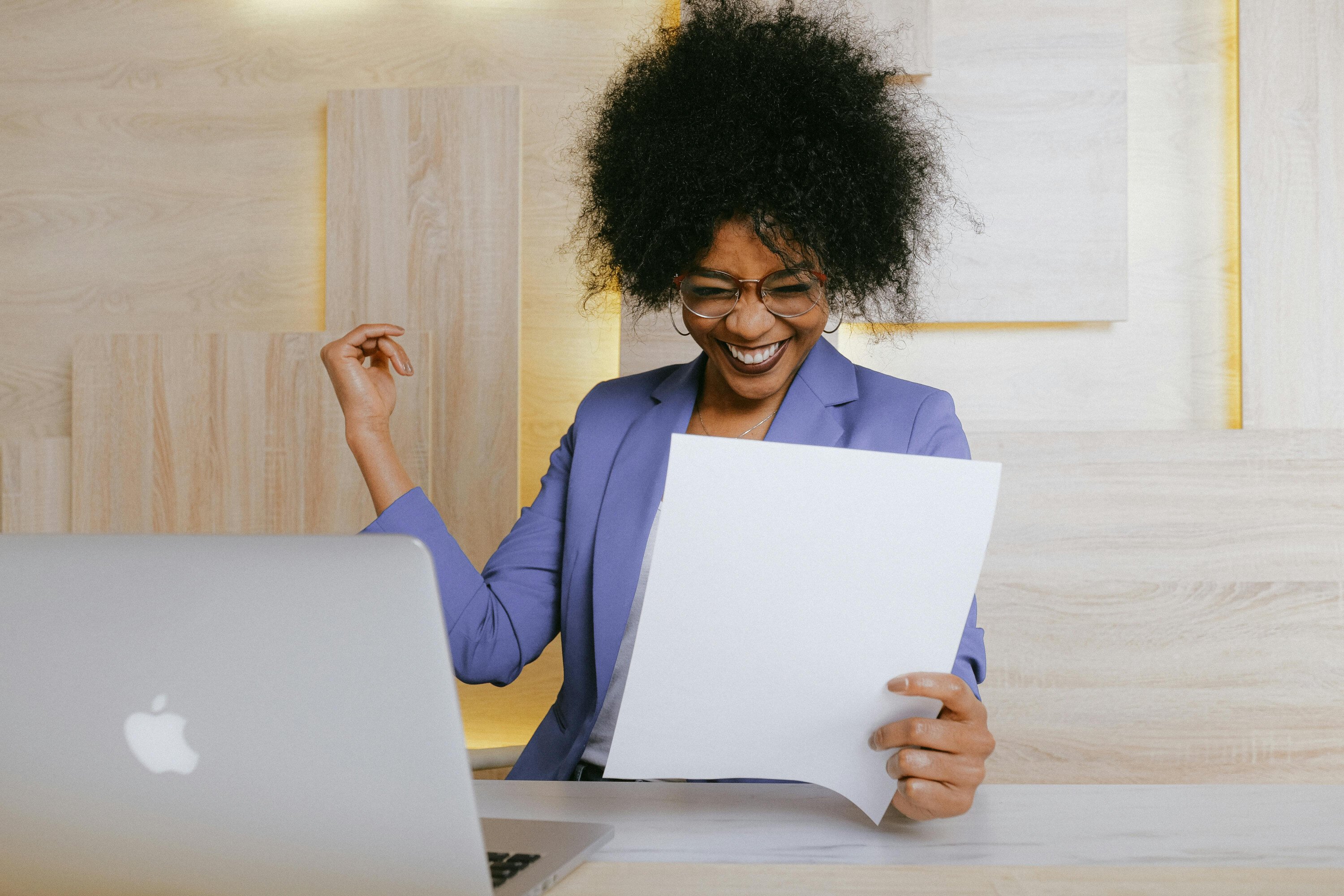 Business woman celebrating while looking at sheet of paper.