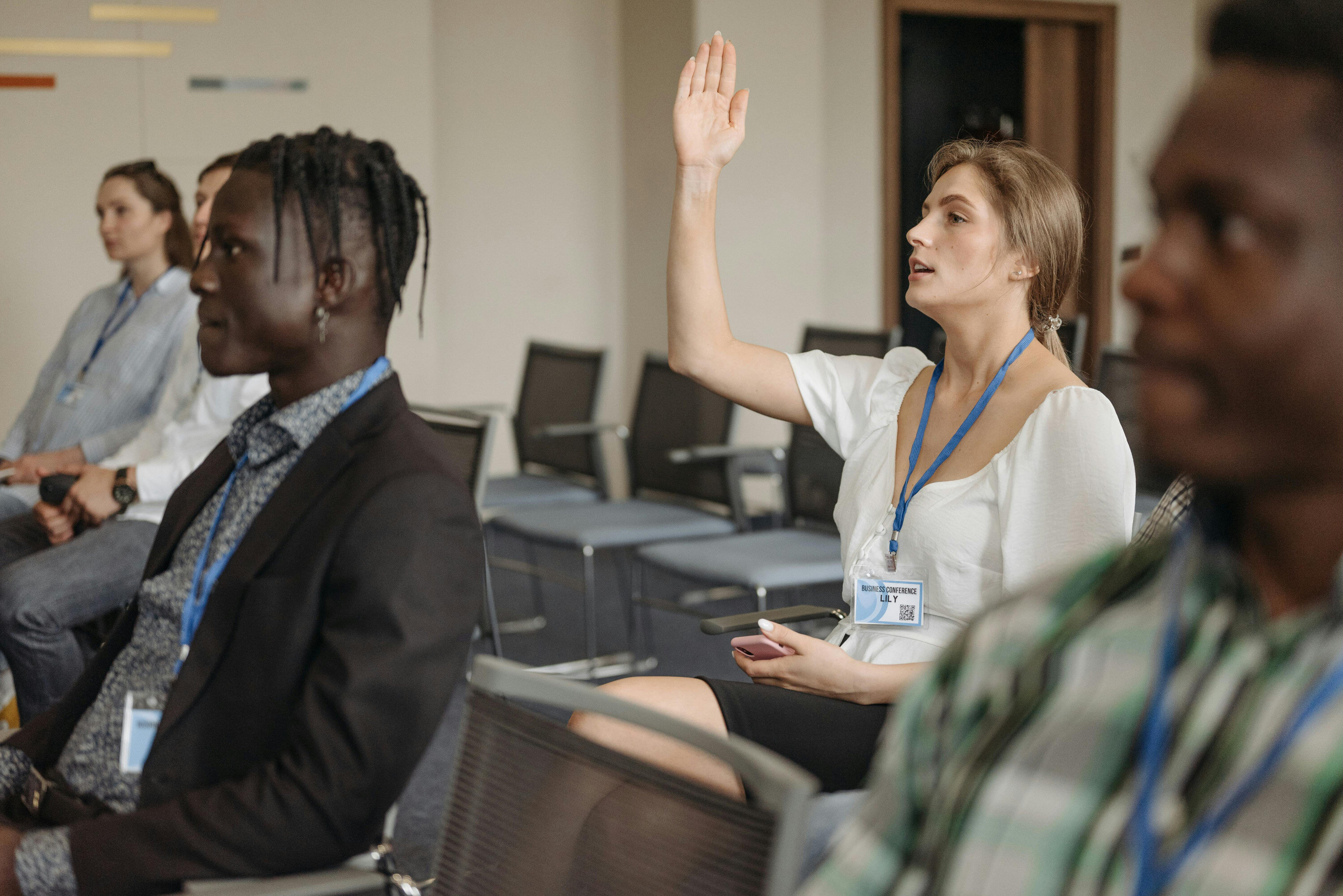 Woman raising her hand in meeting room to ask a question.