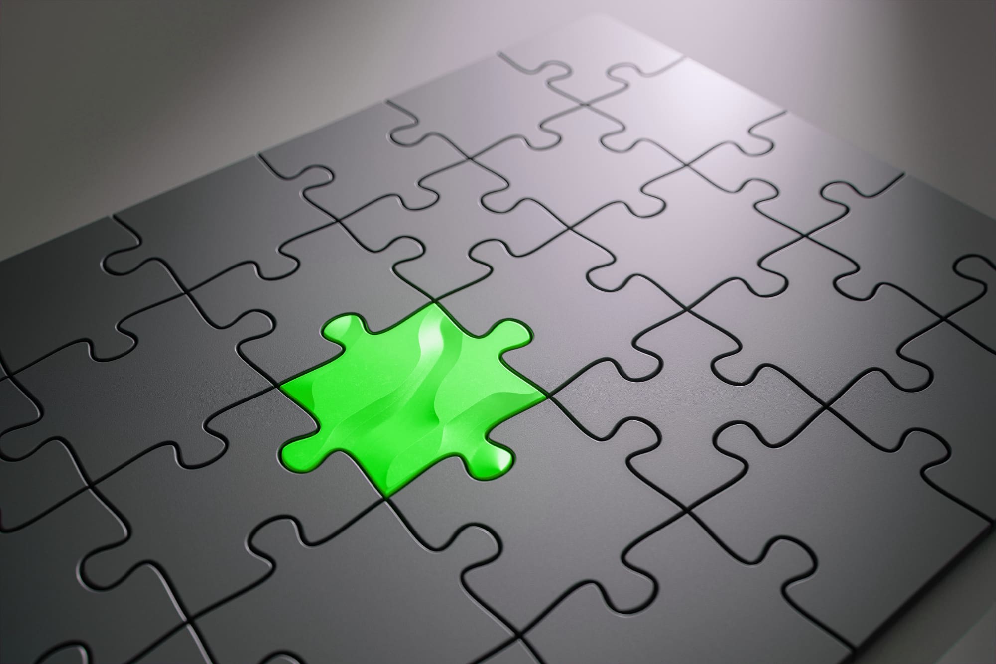 All-grey jigsaw puzzle with one green piece slotted into the middle.