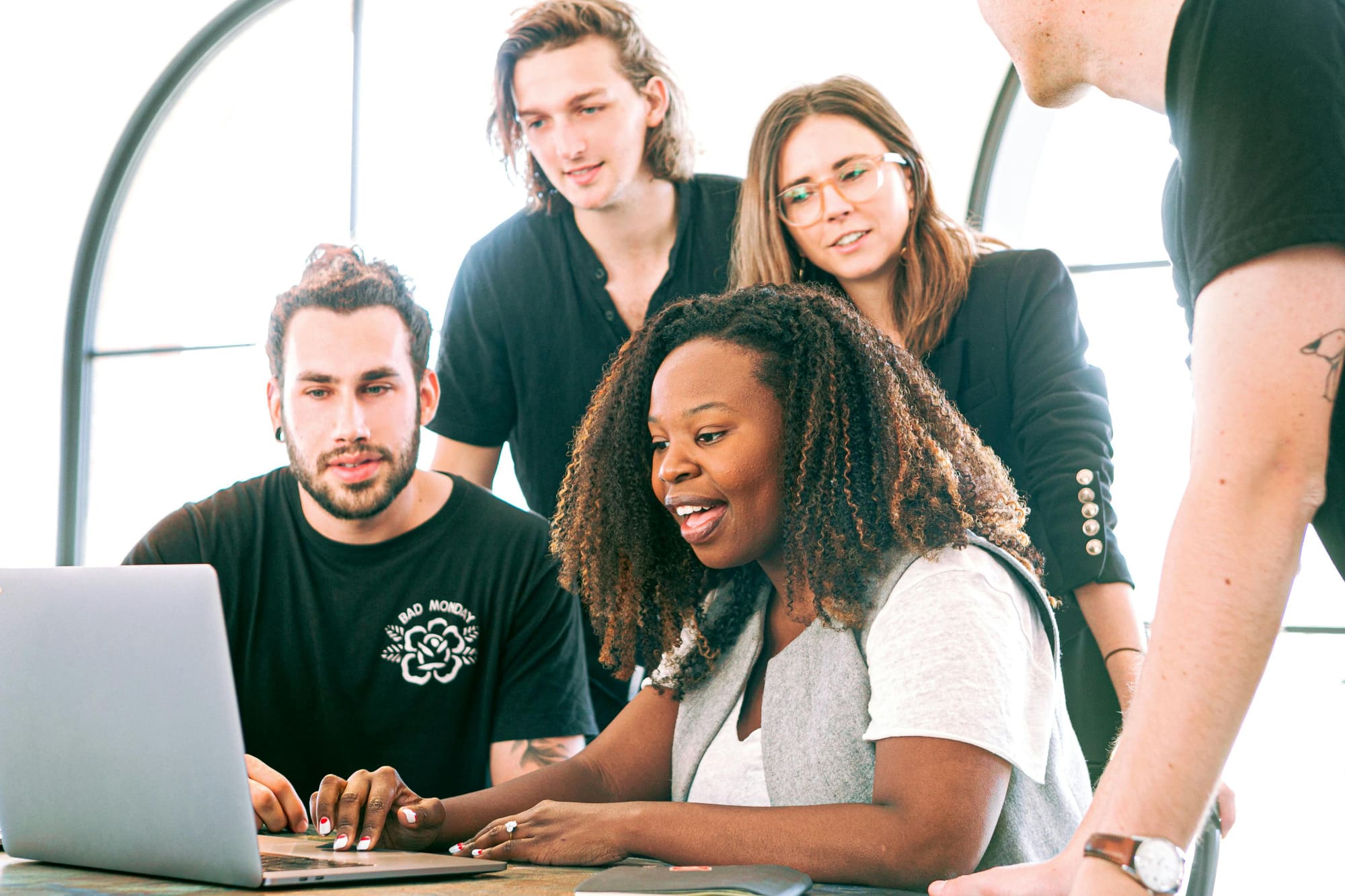 Several office workers crowded around a laptop looking at the screen.
