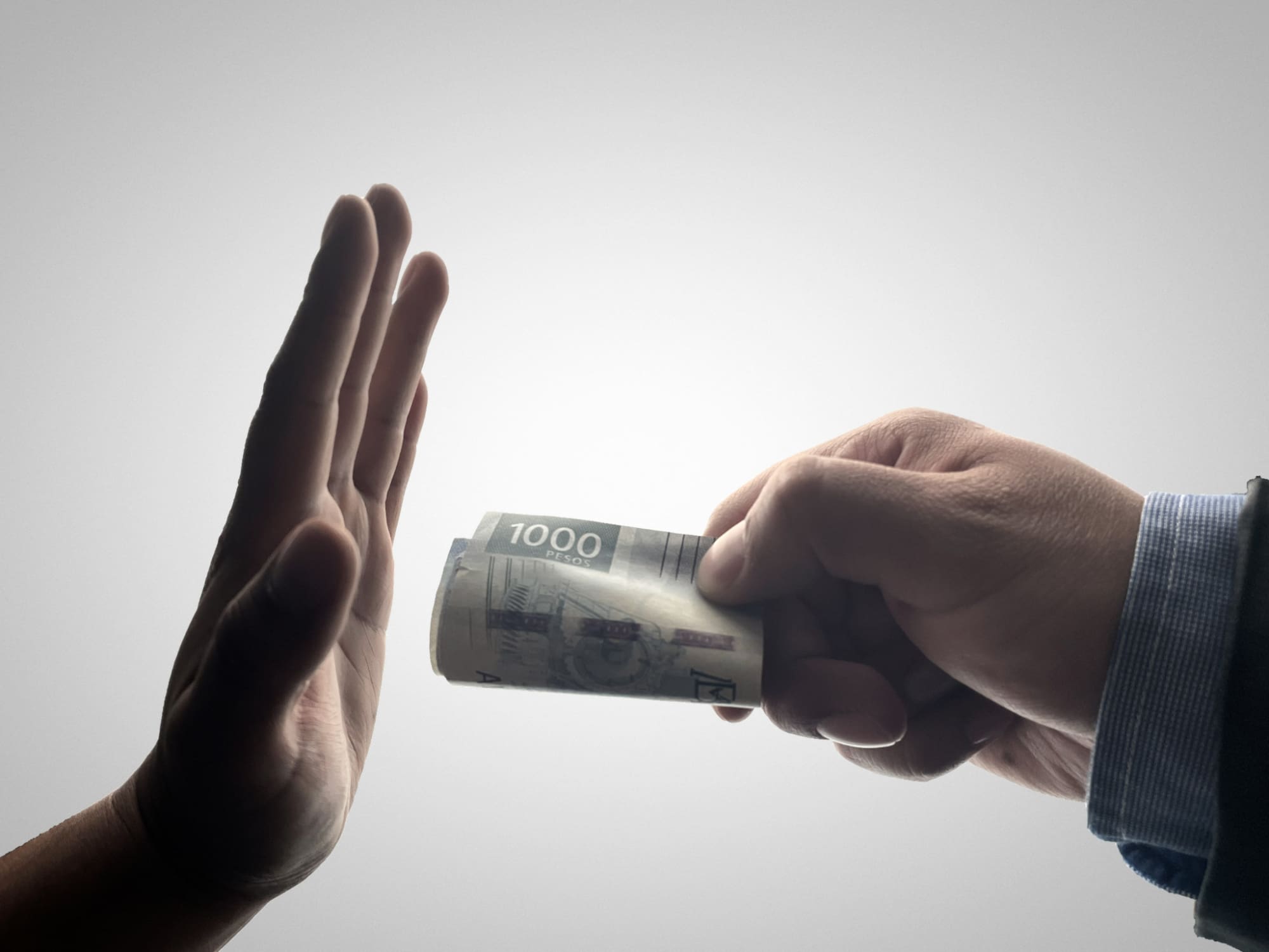A hand refusing another hand offering it money.
