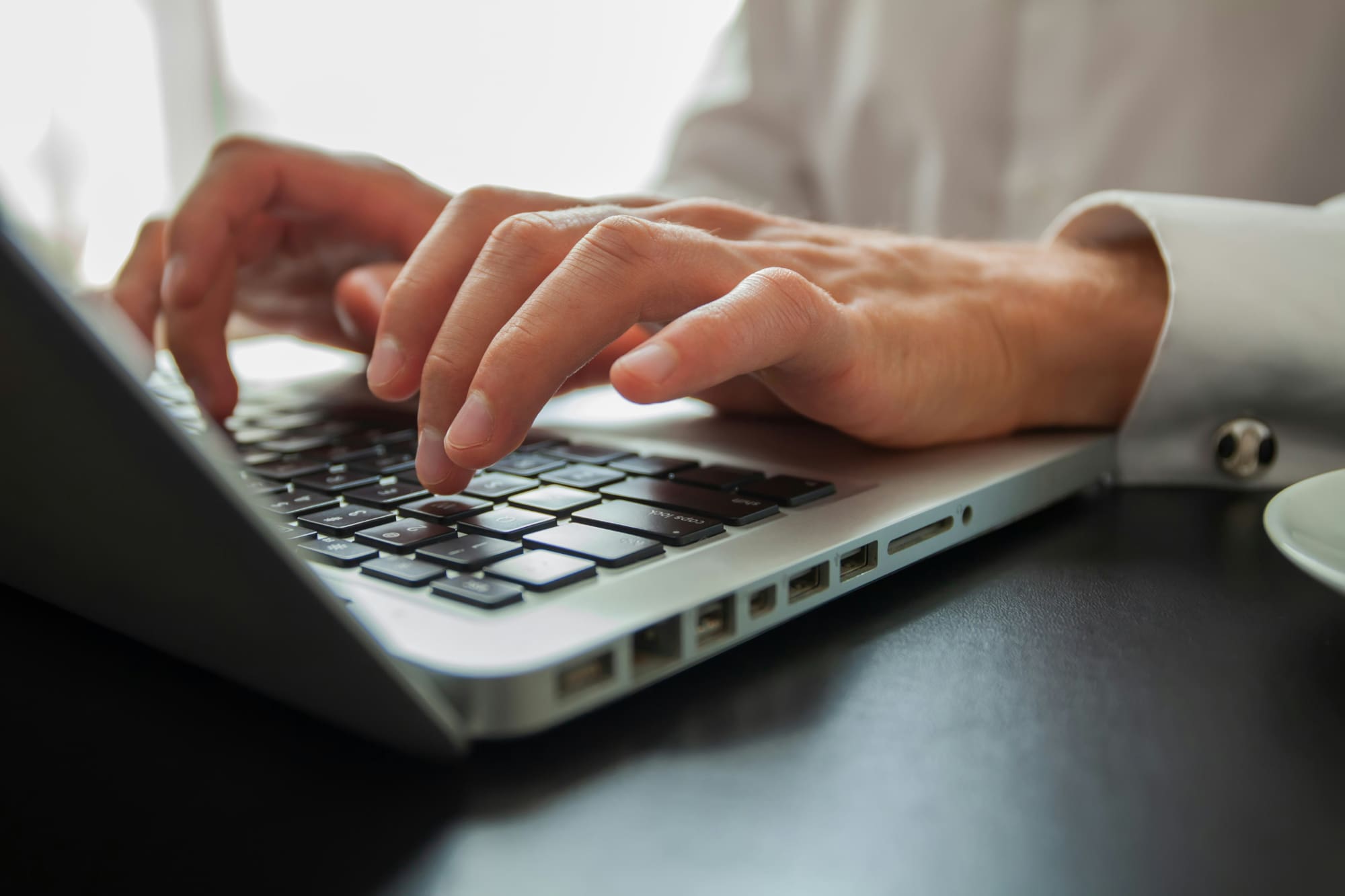 Close-up image of somebody typing on a laptop keyboard.