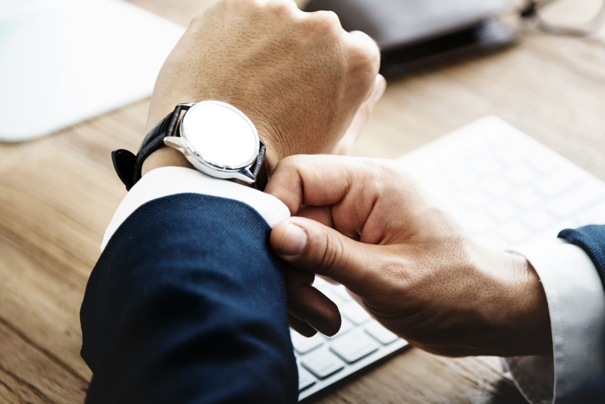 A close-up of a business person's hands with particular focus on their watch.