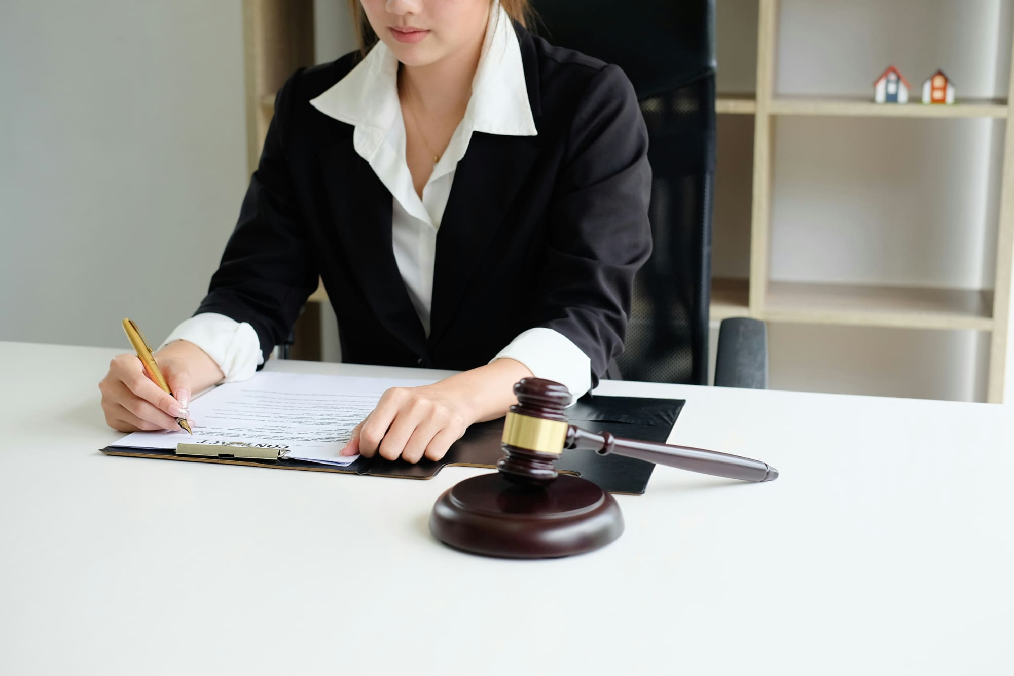 Business person writing on notepad with gavel in front of them.