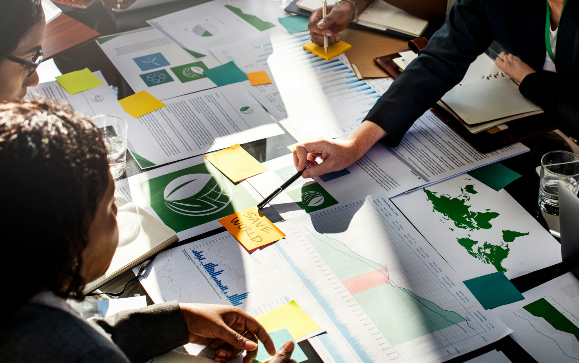A business person pointing to a sticky note that says 'save world' which is part of a wider sustainability plan.