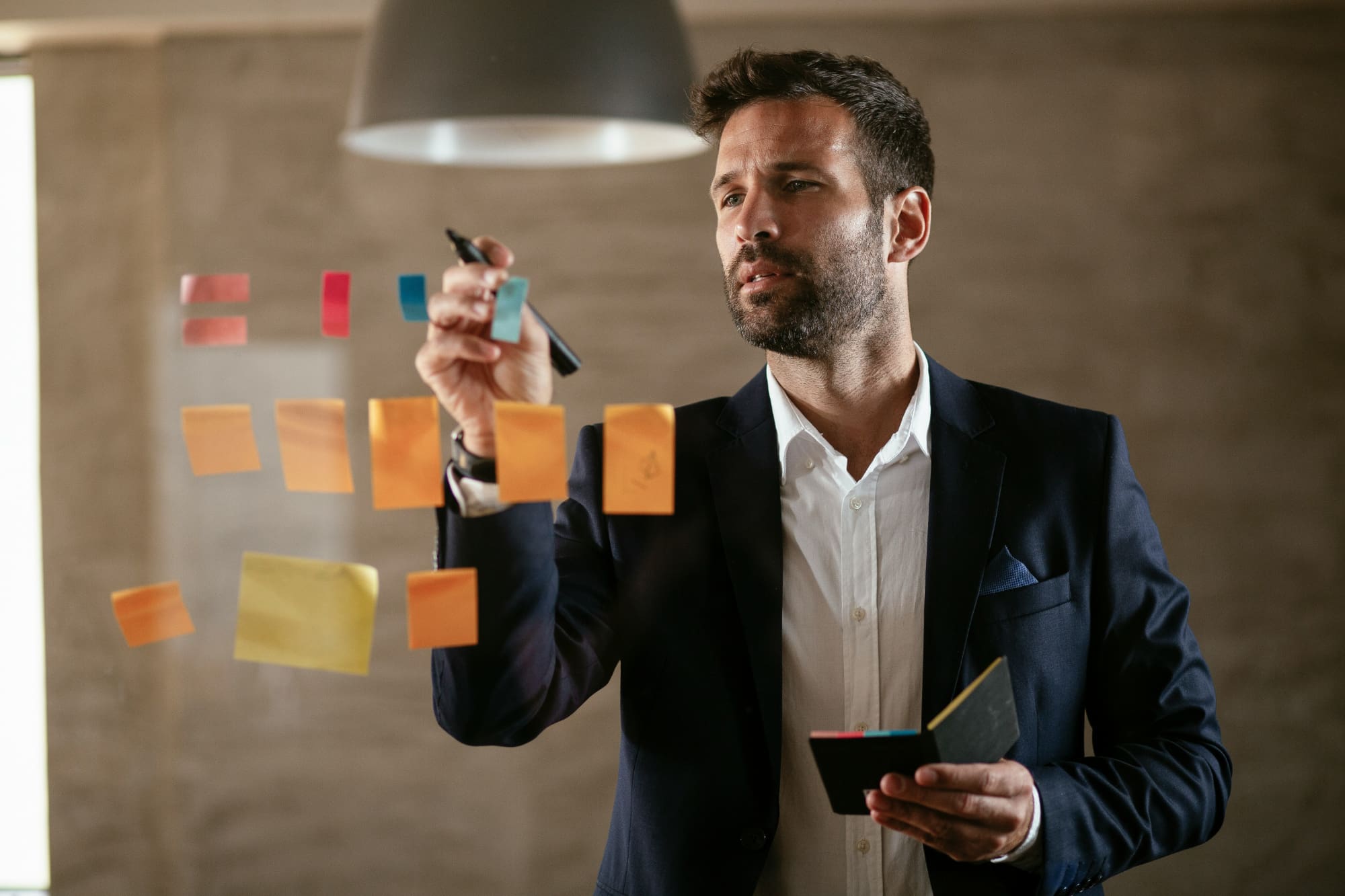 Guy placing post-it notes on glass wall.
